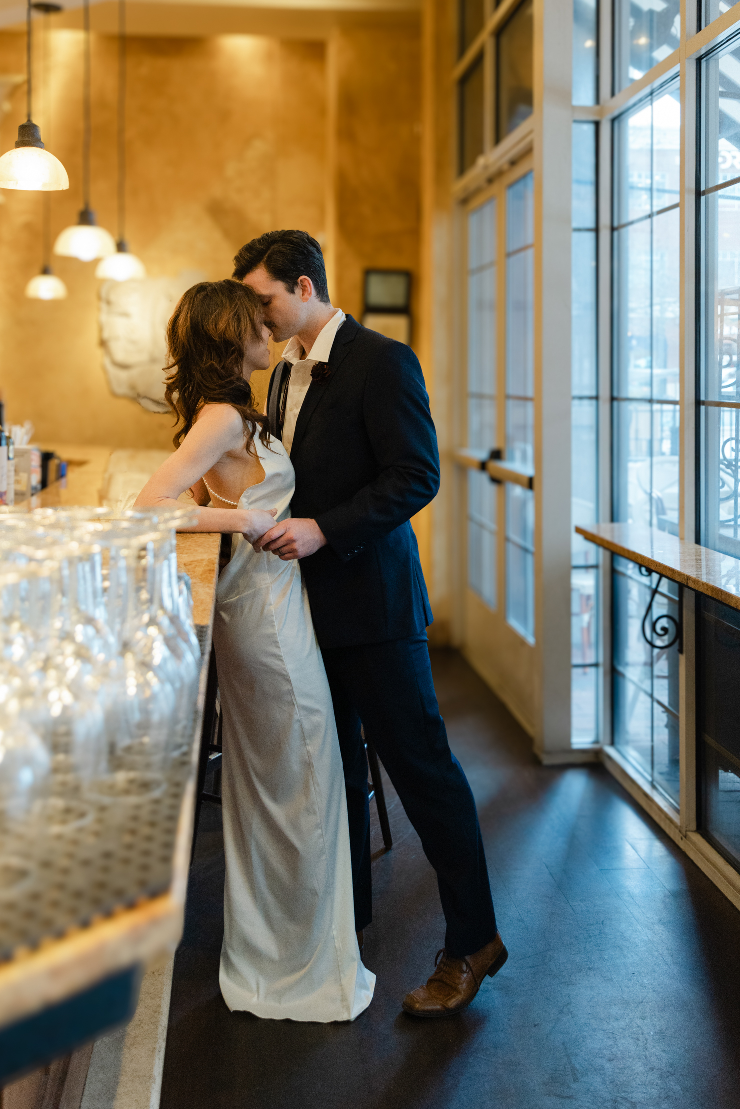 Virginia Beach engagement photography of a bride in a white dress and a groom in a tux standing near the bar facing each other