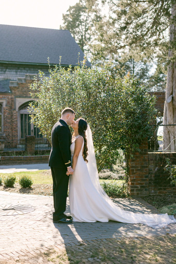 Hermitage Museum and Gardens  wedding photography of a bride and groom standing in front of a bush, holding hands and kissing