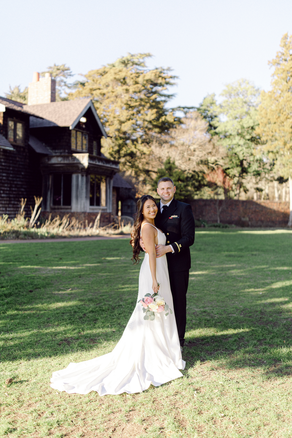 Hermitage Museum and Gardens  wedding photography of a bride and groom standing in front of a historical building and smiling, taken by Virginia wedding photographers Glenn and Nadya. 