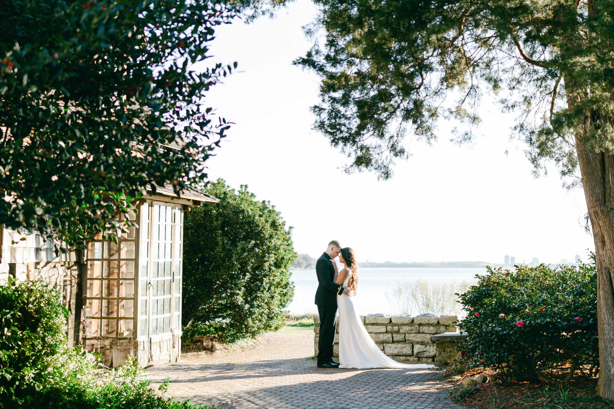 Hermitage Museum and Gardens  wedding photography of a bride and groom standing under the tree in front of a historical building facing each other, taken by Virginia wedding photographers Glenn and Nadya. 