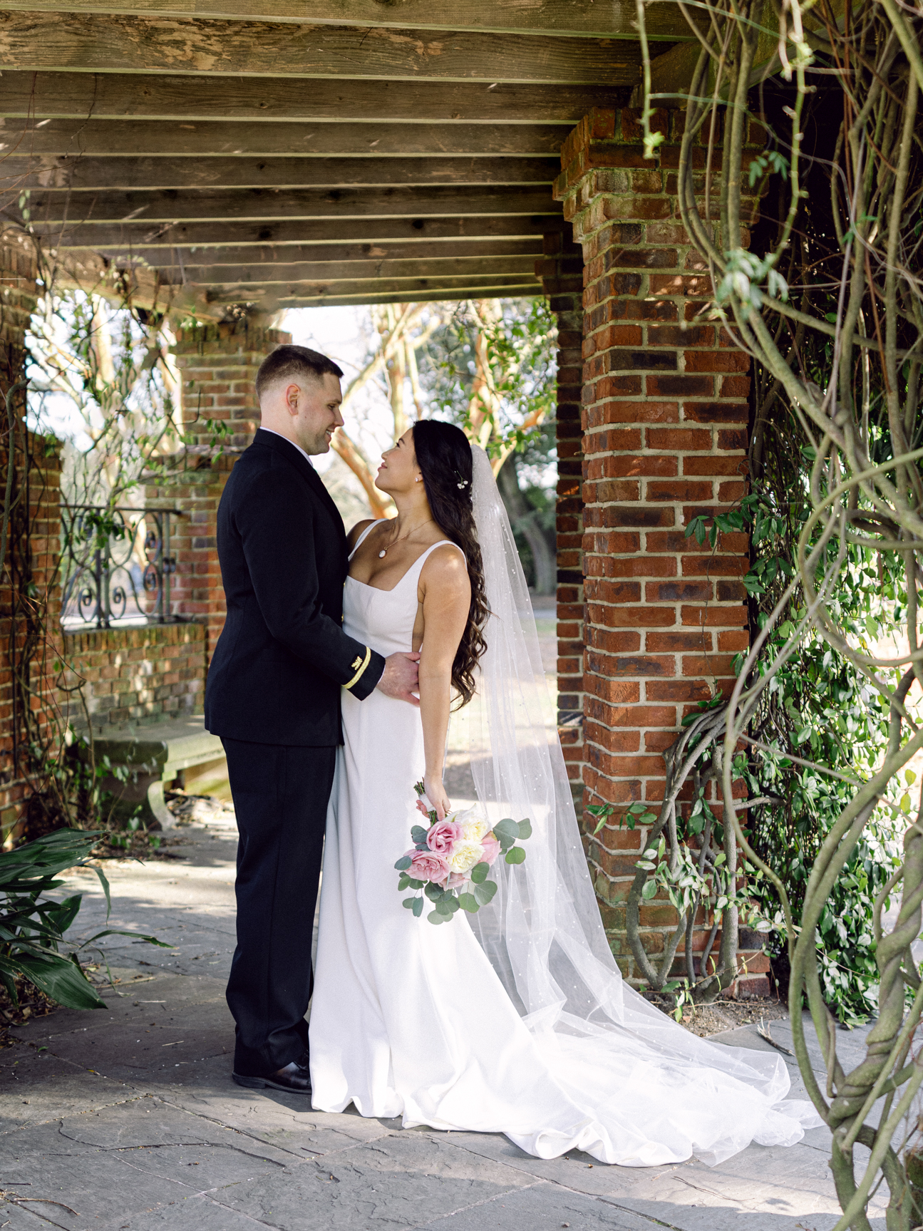 Hermitage Museum and Gardens  wedding photography of a bride and groom standing under a pergola,  looking at each other, taken by Virginia Beach wedding photographers Glenn and Nadya