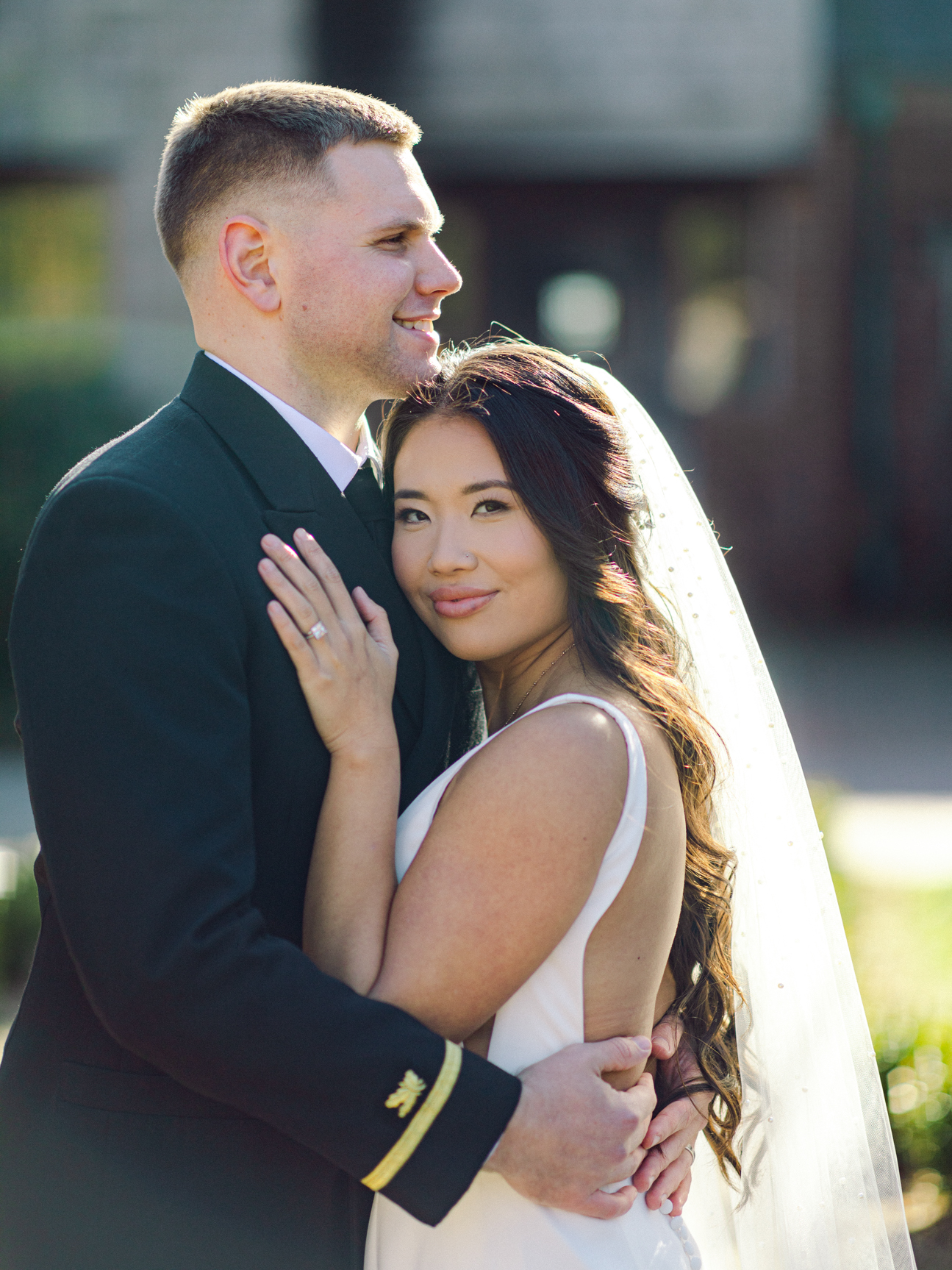 Close up image of a bride and groom standing in front of a historical building hugging each other at the Hermitage Museum and Gardens  