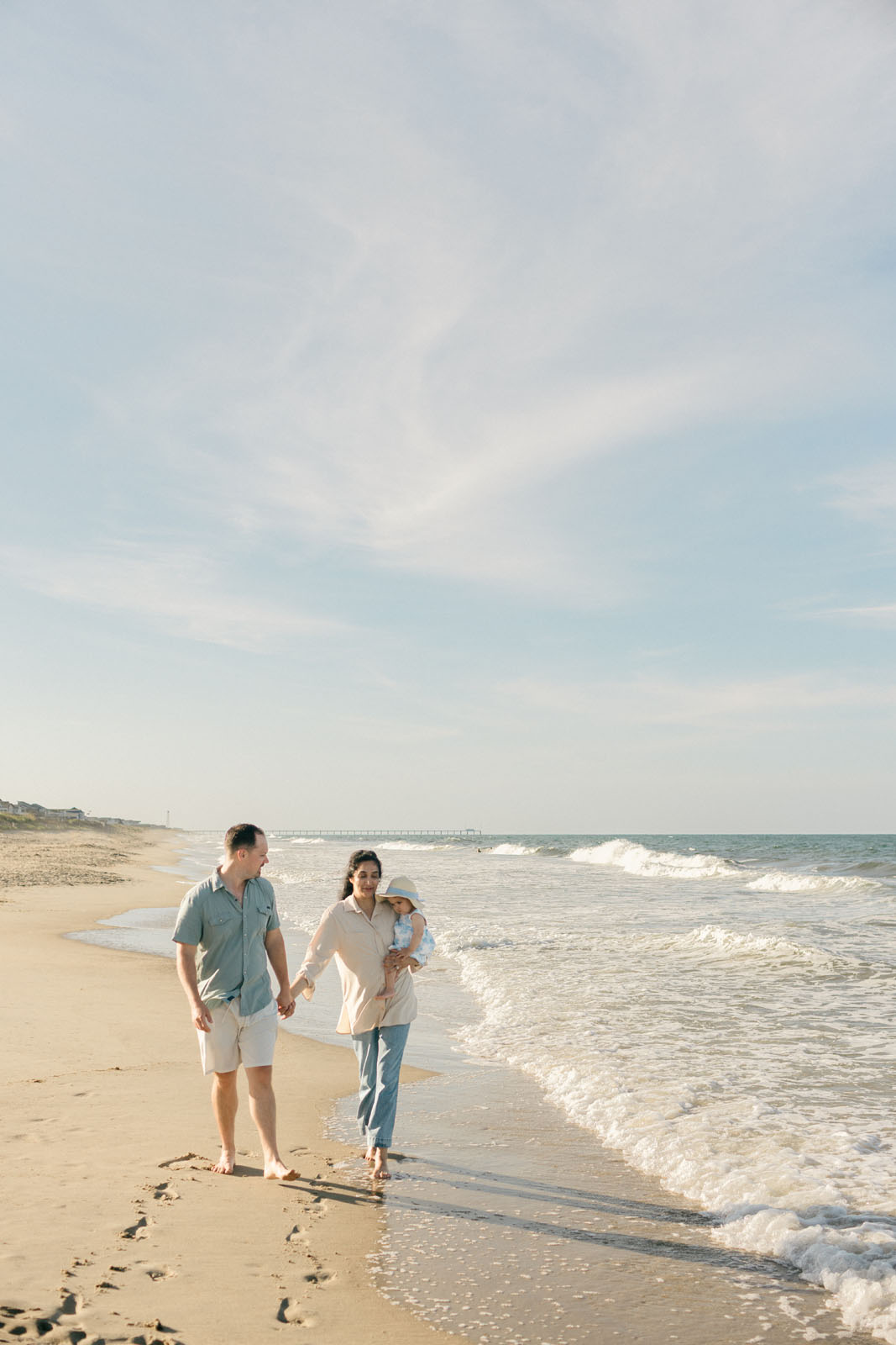 parents walking on the beach with their baby