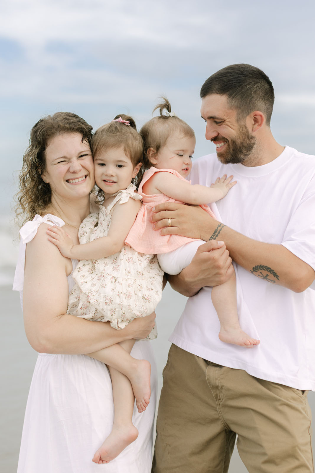 Outer Banks family photography session with parents holding their young daughters on the beach
