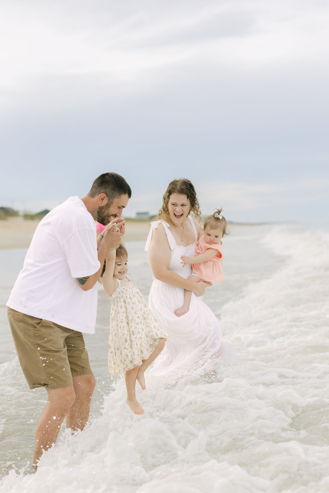 Family playing in the ocean waves during a sunset photo session on the Outer Banks

