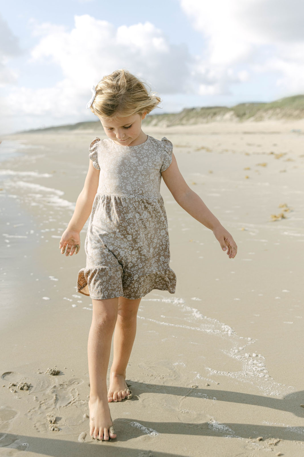 A little girl playing near the ocean during a family session in Kitty Hawk