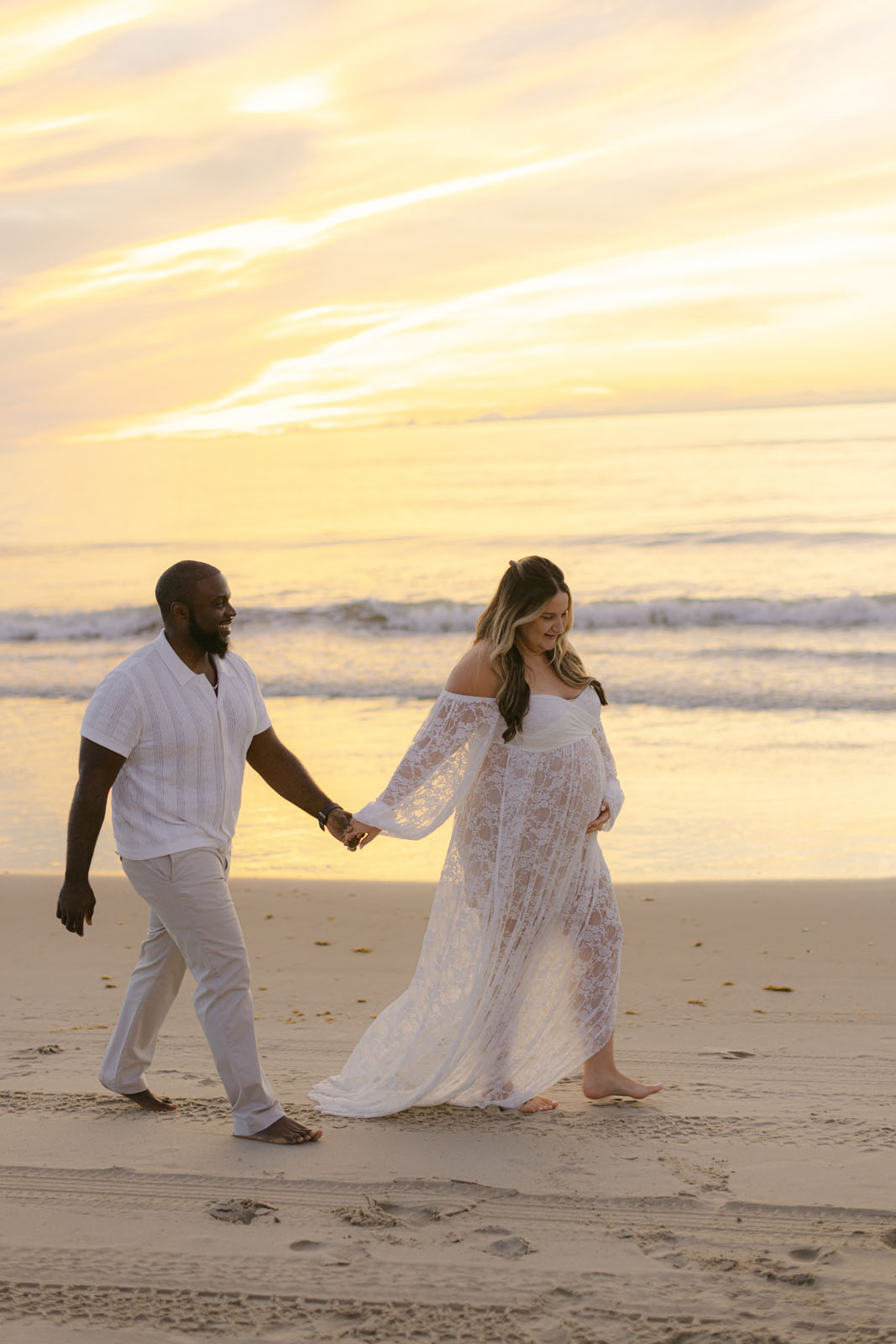 Couple walking along the beach during a sunrise photo session on the Outer Banks